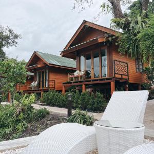 a wooden house with a white chair in front of it at Mangrove bungalow & restaurant in Ko Kood +99 photos