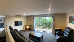 a living room with leather furniture and a large window at Sun Saturated sanctuary in Timaru