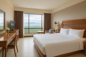 Una habitación de hotel con una cama, un escritorio y una ventana. en Loei Palace Hotel, en Loei