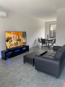 a living room with a couch and a flat screen tv at Springvale 3 Bedroom Town House - Best Location in Springvale +42 photos