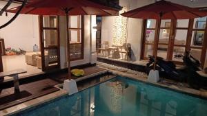 a swimming pool with two umbrellas in a building at Padma Laya Private Villa 2BR in Sukawati