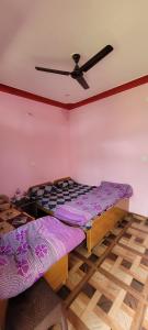 a bedroom with two beds and a ceiling fan at Anushka vatika in Phata
