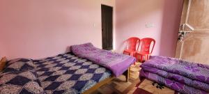 a bedroom with a bed and two red chairs at Anushka vatika in Phata