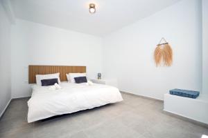 a bedroom with a white bed and a wall at Muse Studios & Apartments in Agia Marina Aegina