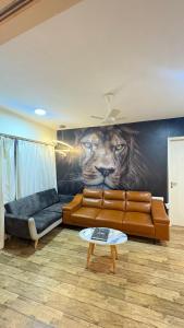 a living room with a couch and a lion mural at 7 Star homes at Rajhans Belliza in Surat +2 photos