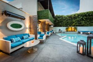 a patio with a blue couch and chairs next to a pool at Mosaic Hotel Beverly Hills in Los Angeles