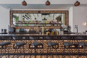 a bar with black stools in front of a mirror at Hotel Figueroa, Unbound Collection by Hyatt in Los Angeles