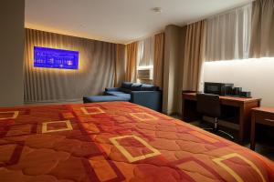 Una habitación de hotel con una cama grande y un escritorio. en Hotel Pergola Jamaica JFK, en Queens