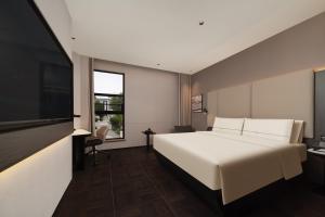 Schlafzimmer mit einem weißen Bett und einem Flachbild-TV in der Unterkunft Atour Hotel Shanghai The Bund Yuyuan Subway Station in Shanghai