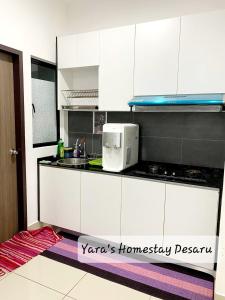 une cuisine avec des armoires blanches et un micro-ondes dans l'établissement Yara's Homestay at Desaru Utama Residence, à Bandar Penawar