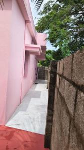 a hallway of a pink building next to a wall at kanyakumari home stay in Jāmb +1 photo