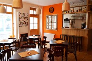 a restaurant with tables and chairs in a room with orange walls at Rathaus-Pension 1685 in Brandenburg an der Havel