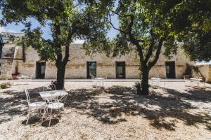 a group of tables and chairs under two trees at Ai Pilieri di Bagnoli in Castel del Monte