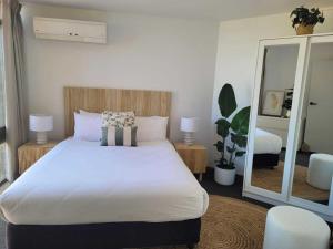 a bedroom with a large white bed and a mirror at Accommodation Portland Victoria in Portland
