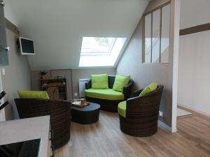a living room with green chairs and a skylight at Les caves Sainte Anne in Écommoy