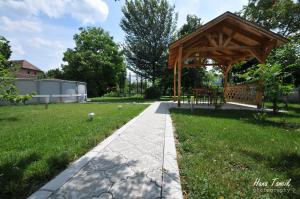 a wooden gazebo in a park with a sidewalk at Apartments Svetlica in Bački Petrovac +11 photos