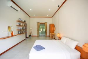 a bedroom with a large white bed and a chair at บ้านครีมครูเมย์ พูลวิลล่า in Ban Nong Ban Kao +3 photos