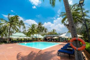 a swimming pool with blue lounge chairs and a tree at Thai Hoa Mui Ne Resort in Mui Ne