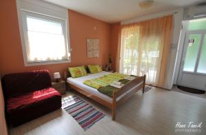 a bedroom with a bed and a couch and a window at Apartments Svetlica in Bački Petrovac
