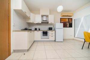 a kitchen with white appliances and a yellow chair at Modern 1 bedroom flat in Strovolos