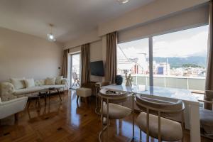 a living room with a table and chairs and a large window at Central Luxury Penthouse in Kalamata