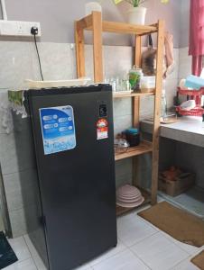 a black refrigerator in a kitchen next to a shelf at Homestay MMr in Temerloh +2 photos