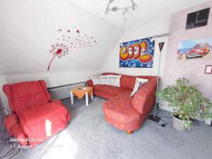 a living room with a red couch and a chair at Ferienwohnung Kochel mit Wallbox in Gifhorn