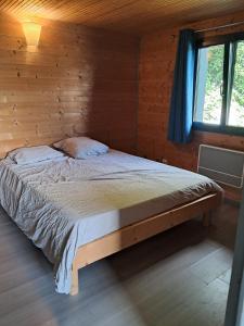 Ce lit se trouve dans une cabane en rondins dotée d'une fenêtre. dans l'établissement Gîte Les Balcons des usses, à Frangy