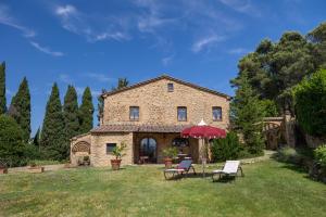 a large stone house with chairs and an umbrella at Podere del Botruccio in Pomarance
