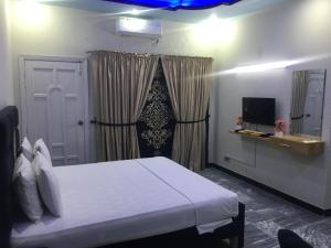 a bedroom with a white bed and a television at SJ Rezidor Guest House in Islamabad