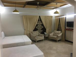 a bedroom with two beds and two chairs and a tv at SJ Rezidor Guest House in Islamabad