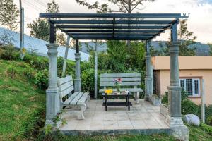 a gazebo with a bench and a table at StayVista at Rustling Pine with Bonfire, BBQ & Lawn in Ooty