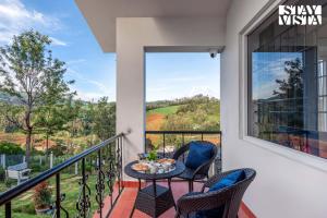 a balcony with a table and chairs and a view at StayVista at Rustling Pine with Bonfire, BBQ & Lawn in Ooty +23 photos