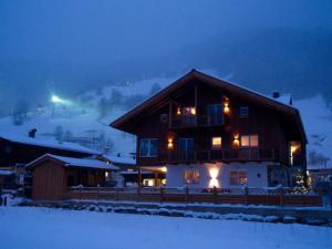 a large wooden house in the snow at night at ff Appartements in Bramberg am Wildkogel