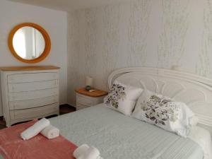 a bedroom with a white bed and a mirror at Casa de Pueblo in Martos +4 photos