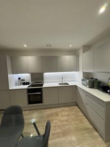 a kitchen with white cabinets and a sink at Exquisite Riverview 2bedroom flat in Manchester. in Manchester +26 photos