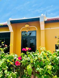 a yellow house with pink flowers in front of it at Laa Hội An in Hiếu Nhơn