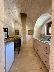 een keuken met een tafel en een stenen muur bij Nidus Petrae in Alberobello