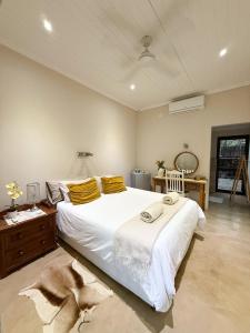 a bedroom with a large white bed with yellow pillows at InniBos Marloth Park in Marloth Park