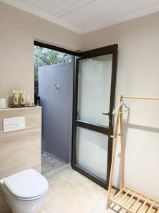 a bathroom with a toilet and a sliding glass door at InniBos Marloth Park in Marloth Park