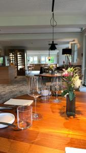 a wooden table with wine glasses and a vase of flowers at OXA - Easy Escape - Bed & Breakfast in Hittisau