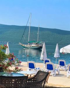 a group of chairs and a boat in the water at Apartman Milica in Herceg-Novi