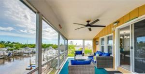 a porch with blue chairs and a ceiling fan at Waterfront Cottage in Marco Island