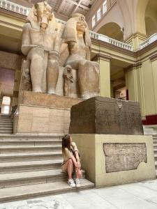 a woman sitting on steps in front of a statue at Magic golden pyramids view in Cairo +13 photos