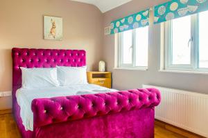 a bed with a pink headboard in a bedroom at Stunning Family Home nr London Harry Potter Tour Pass The Keys in Borehamwood