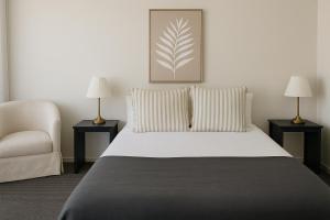 una camera da letto con un letto con due lampade e una sedia di Cooks Endeavour Motor Inn a Tweed Heads