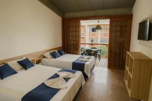 Una habitación de hotel con dos camas y balcón. en Marmeu Tropical (Com garagem), en Guarujá