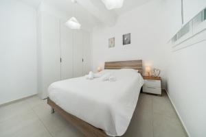 a white bedroom with a large white bed with two towels at 1 bedroom flat in Aglatzia in Aglantzia