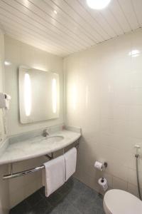 a bathroom with a sink and a mirror and a toilet at ibis Joinville in Joinville