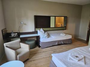 a room with two beds and a chair and a mirror at Schulungszentrum Töplitz in Leest